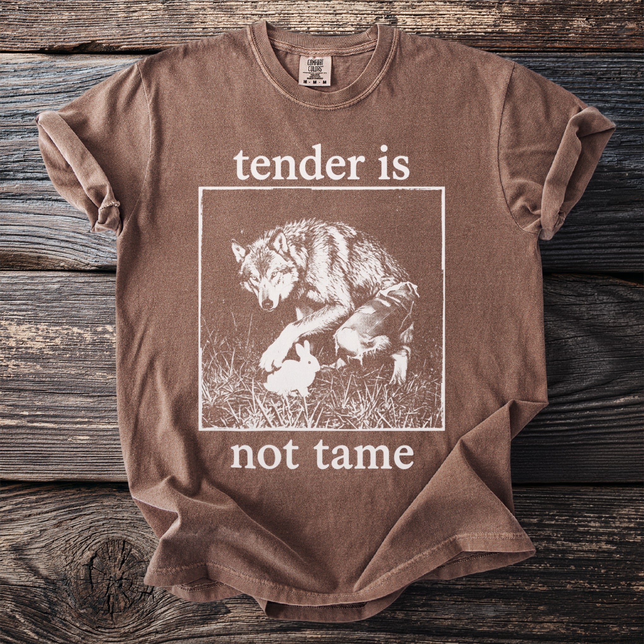 Brown t-shirt with "tender is not tame" and a wolf with a rabbit graphic.