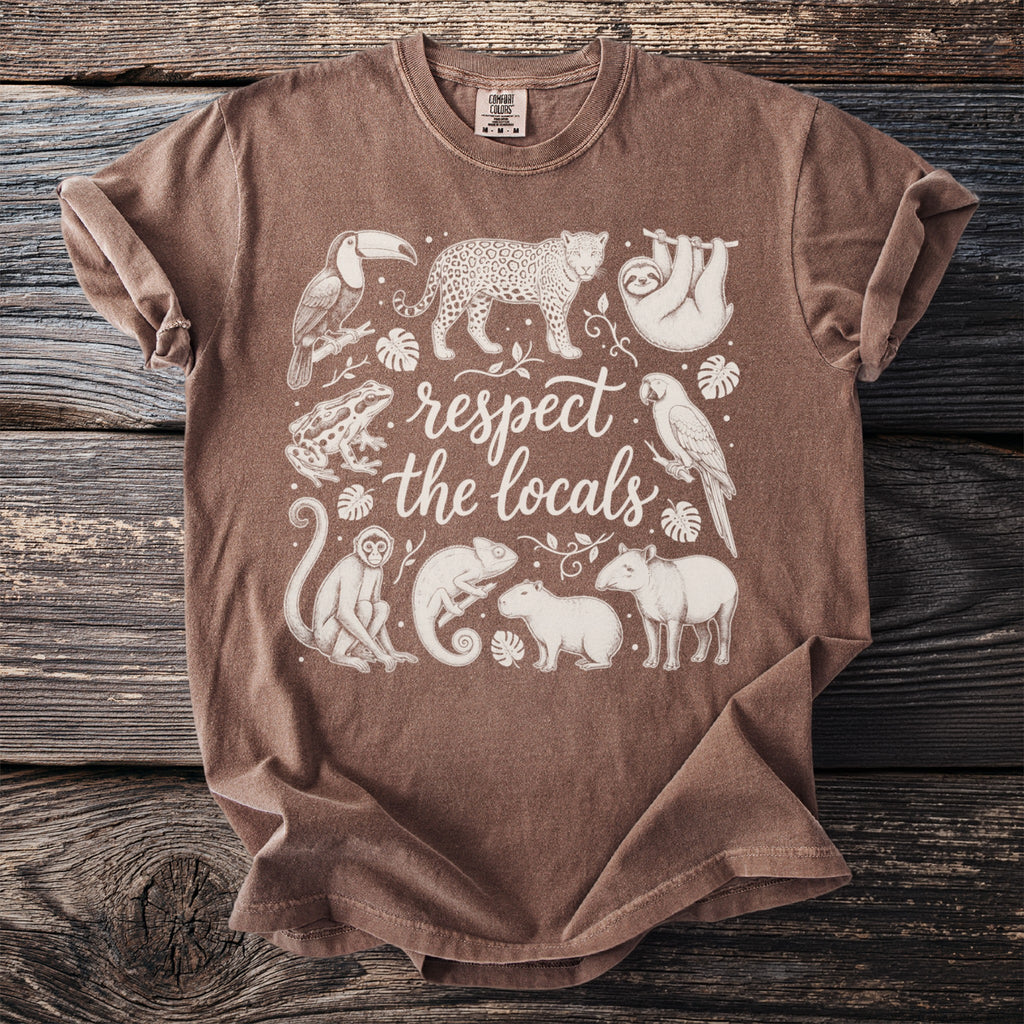 Brown t-shirt with an illustration of rainforest animals and text "respect the locals".