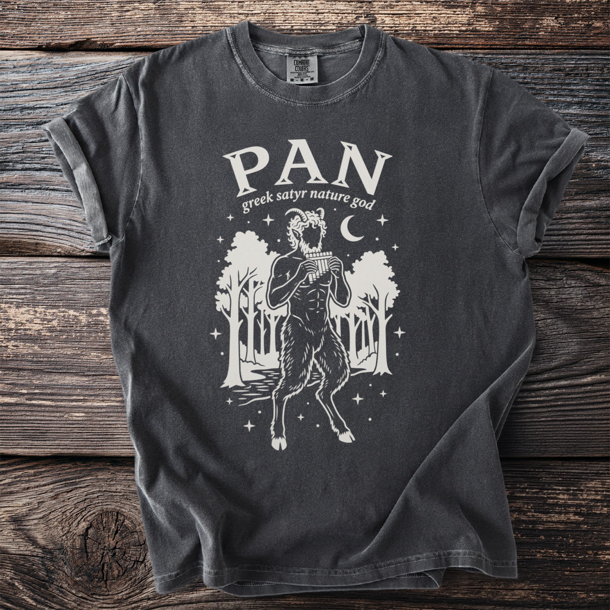 Dark gray t-shirt with white graphic of Pan playing pipes, trees, and moon.