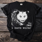 Black t-shirt with a graphic of an opossum and text "i have worms".