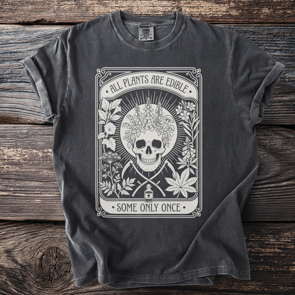 Dark grey t-shirt with a skull, plants, and the text "ALL PLANTS ARE EDIBLE SOME ONLY ONCE".