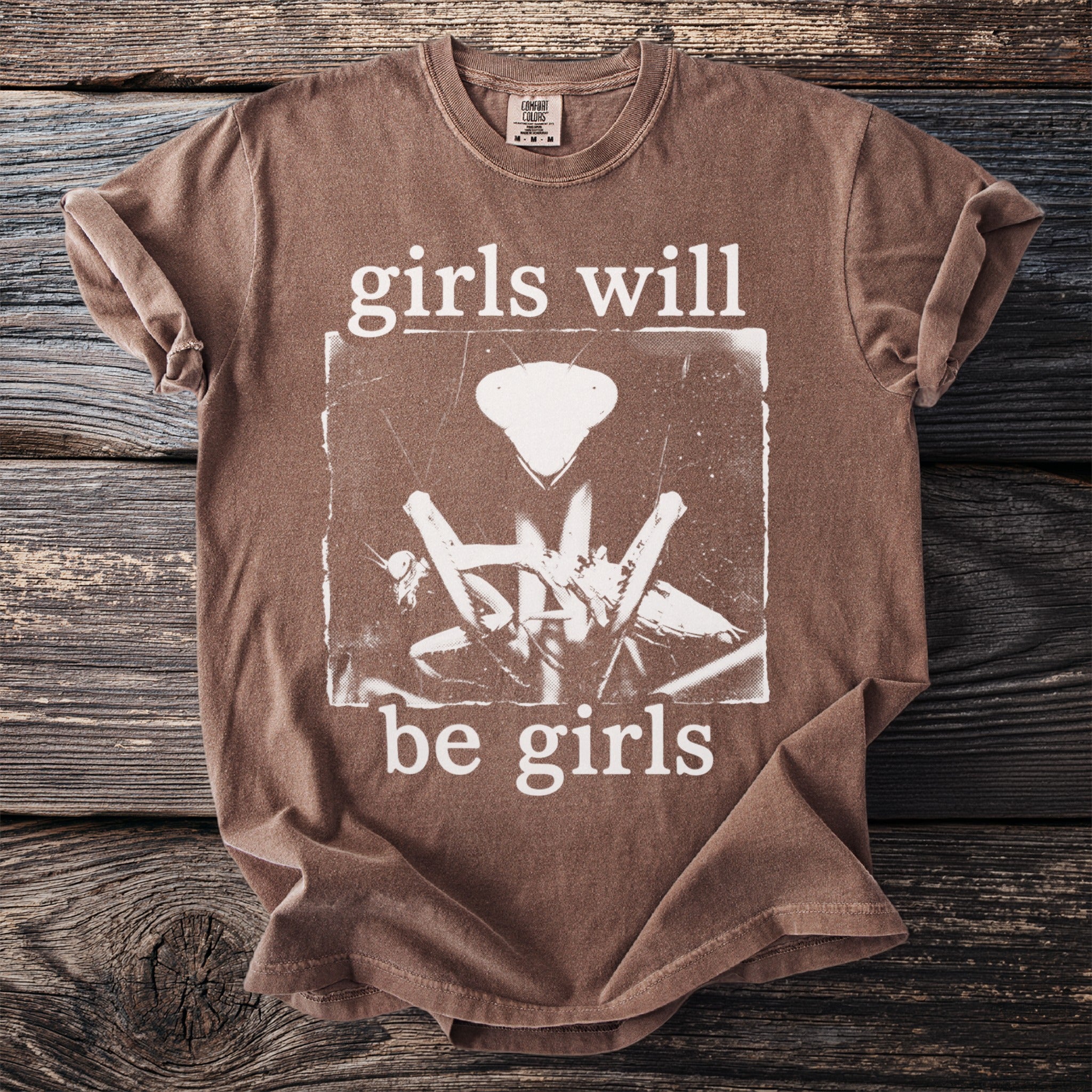 Brown t-shirt with "girls will be girls" and a praying mantis graphic.