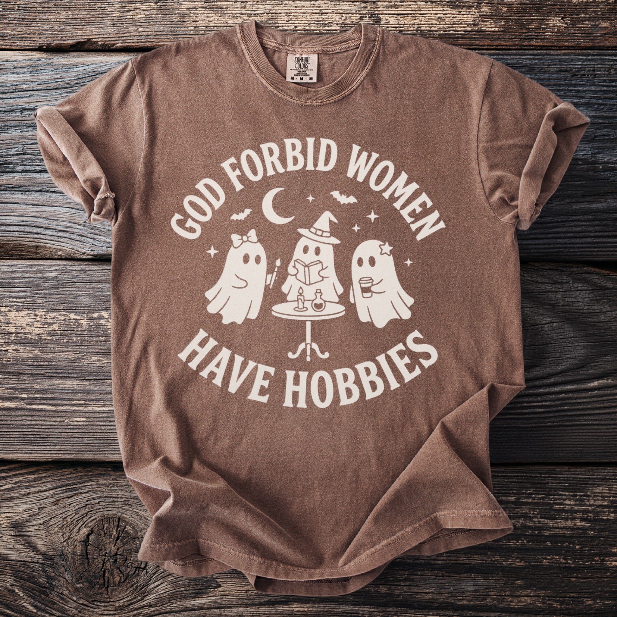 Brown t-shirt with "God forbid women have hobbies" and ghost graphic.