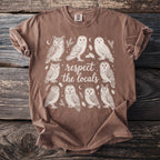 Brown t-shirt with a cream-colored illustration of multiple owls and the text "respect the locals".