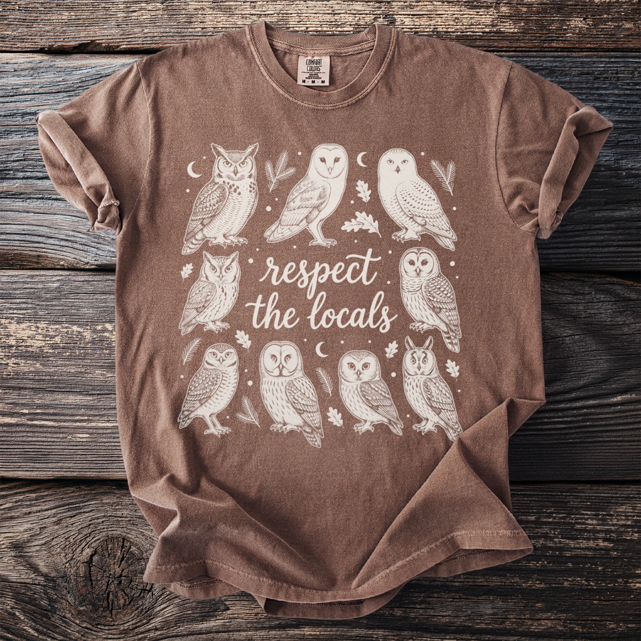 Brown t-shirt with a cream-colored illustration of multiple owls and the text "respect the locals".