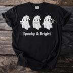 Black t-shirt with three white ghosts wearing Santa hats and text "Spooky & Bright."