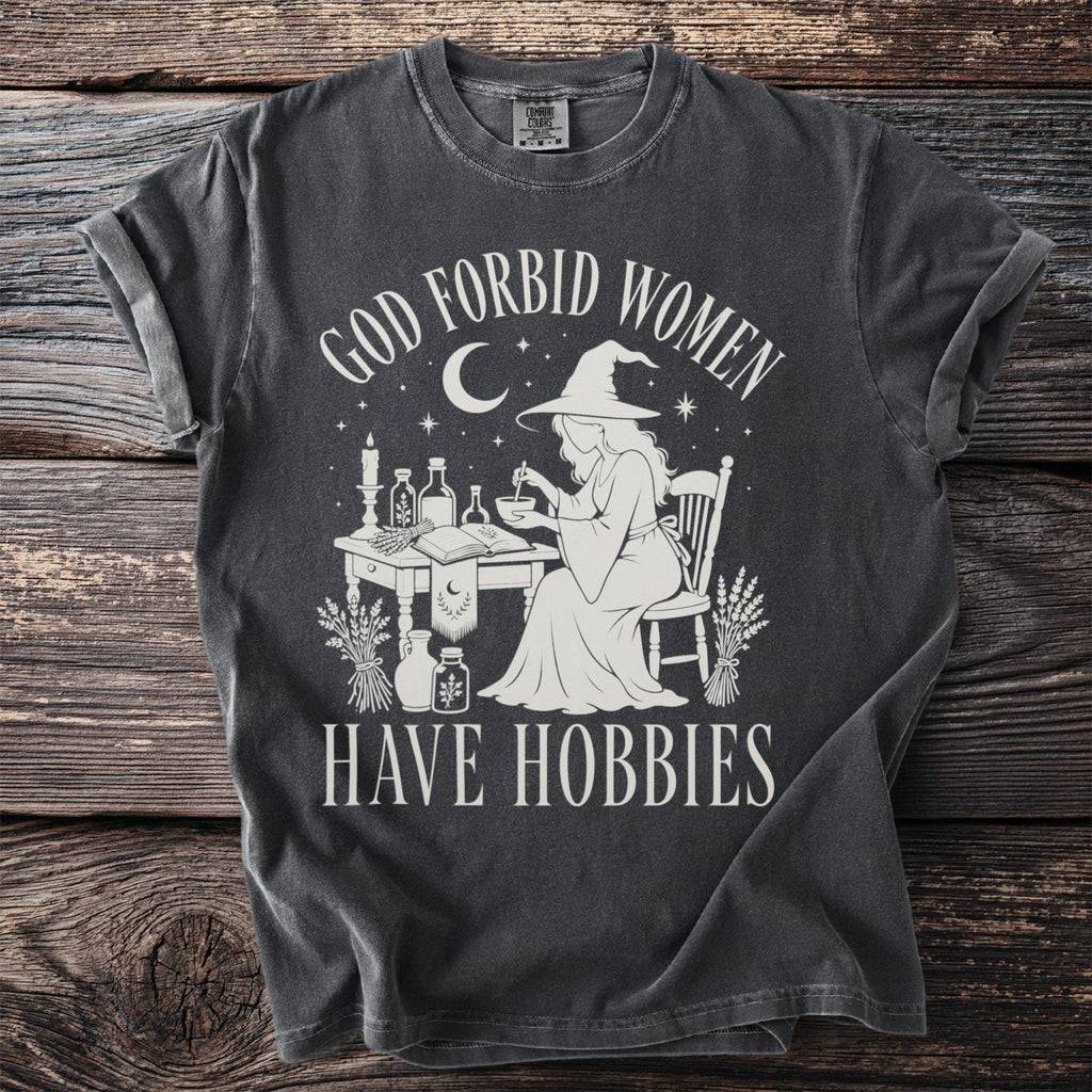 Dark gray t-shirt with "God Forbid Women Have Hobbies" text and witch graphic.