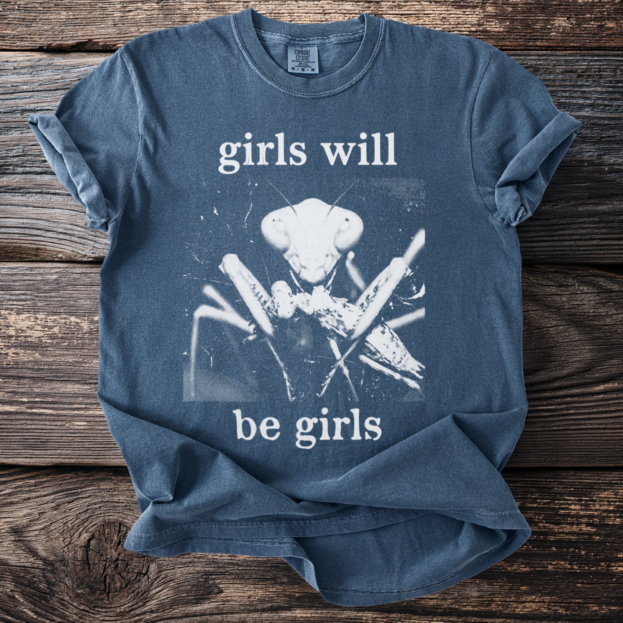 Blue t-shirt with white text "girls will be girls" and a praying mantis graphic.