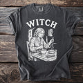 T-shirt with "WITCH" text and illustration of a woman with herbs and mortar.