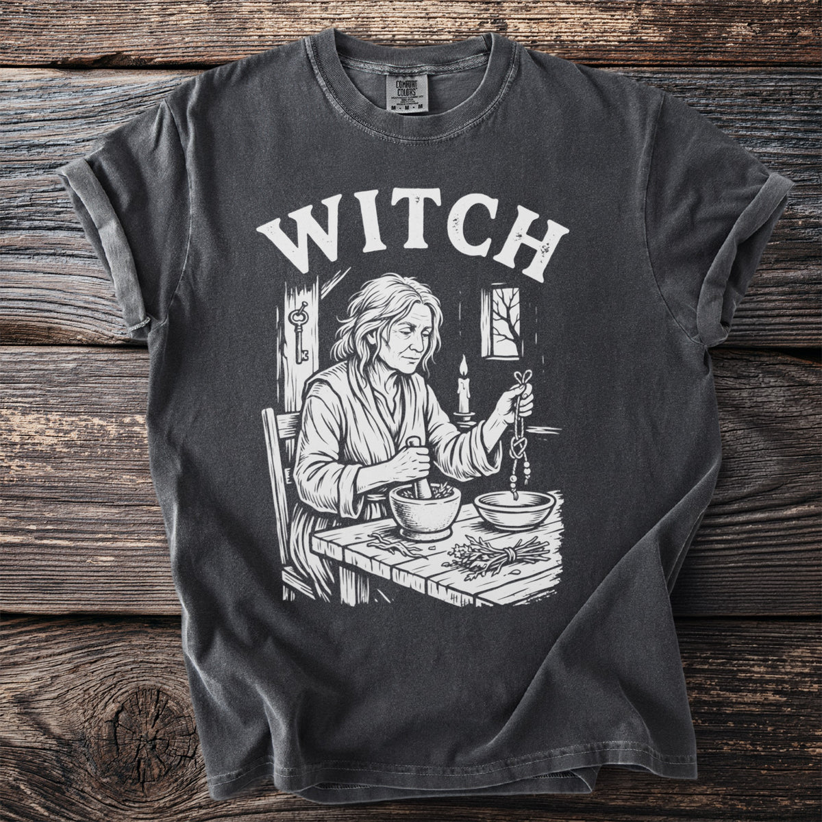 T-shirt with "WITCH" text and illustration of a woman with herbs and mortar.