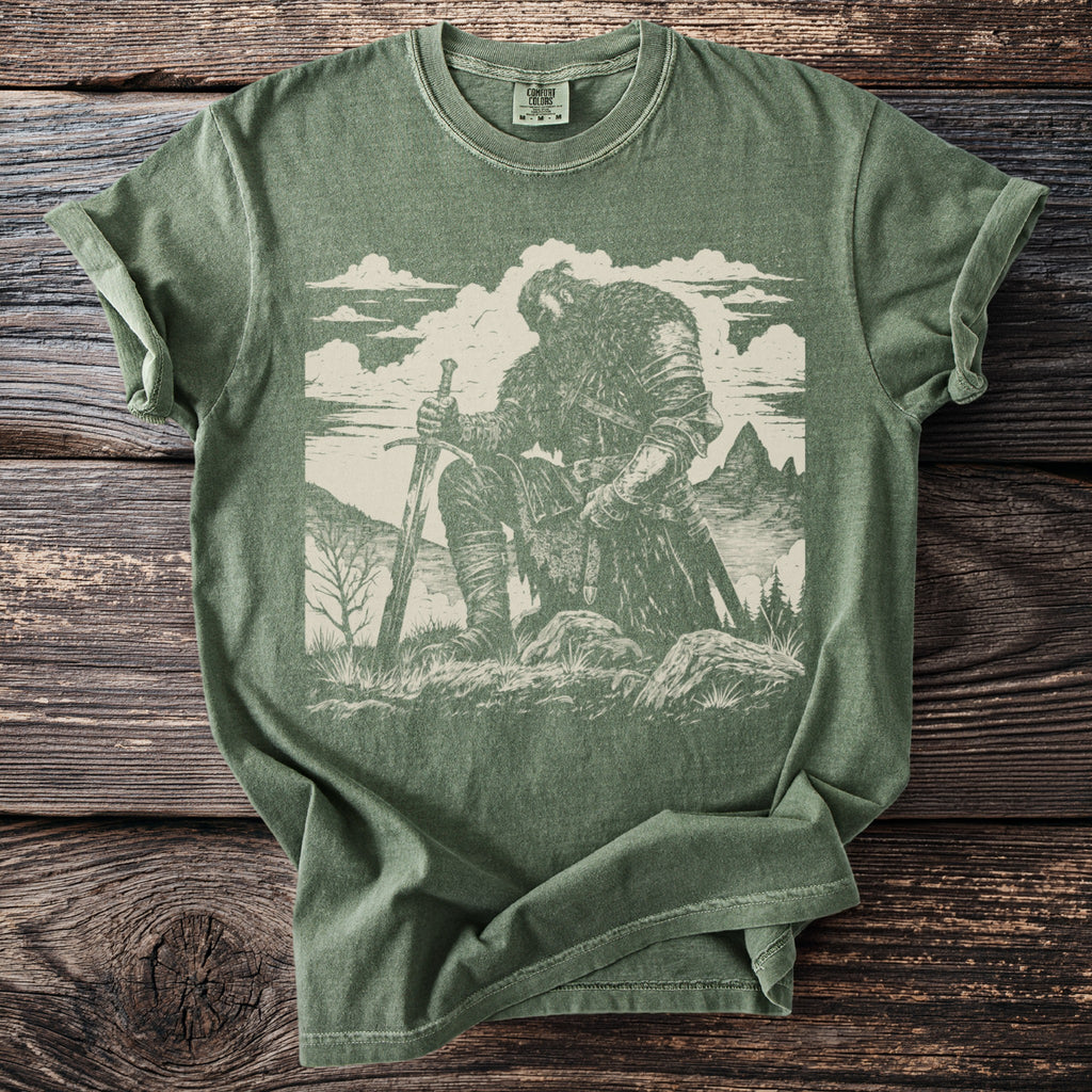 Green t-shirt with a sketched warrior kneeling with a sword, mountains and clouds.