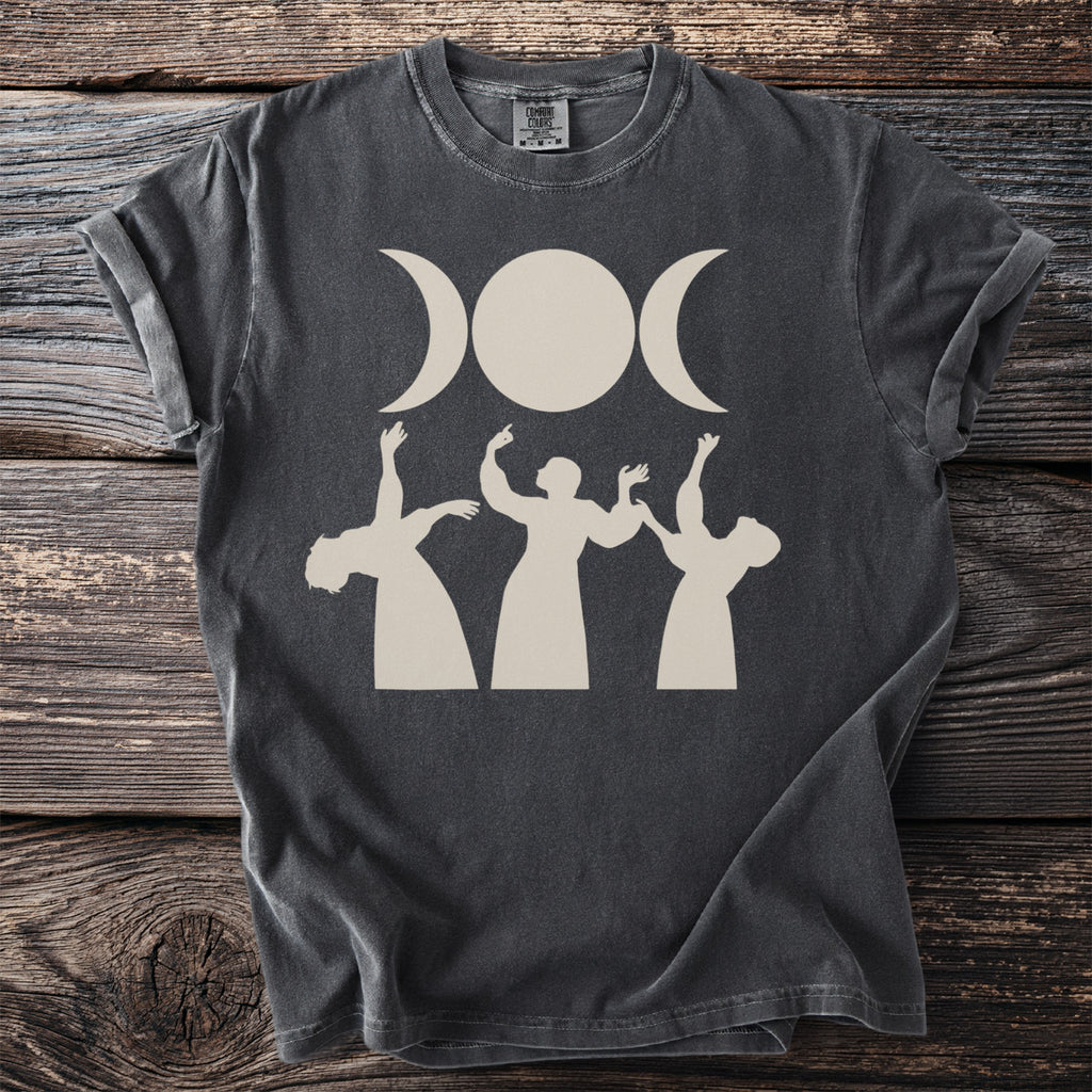 Dark t-shirt with a triple moon goddess symbol and dancing figures.