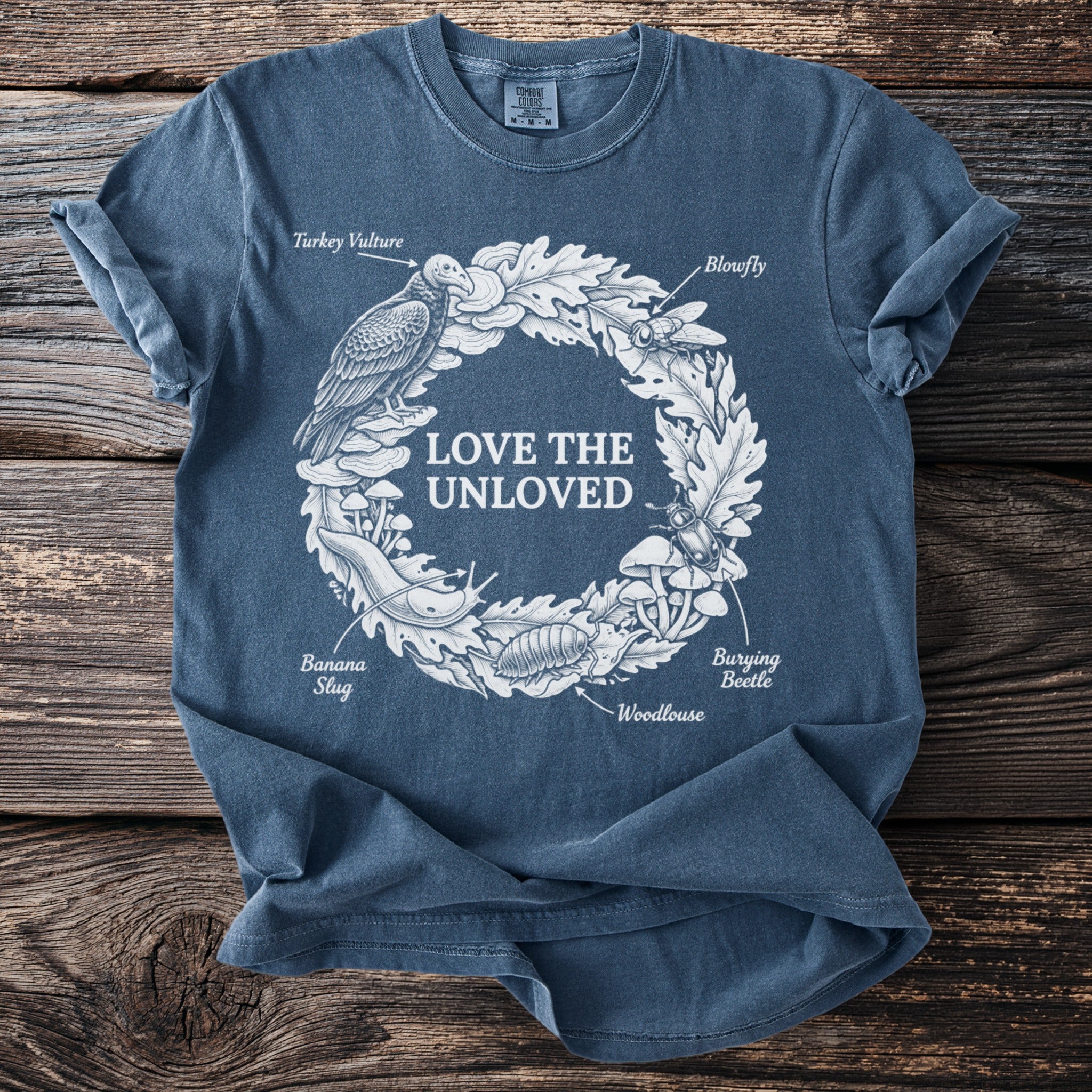 Blue t-shirt with white "Love The Unloved" text and illustrations of natural elements.