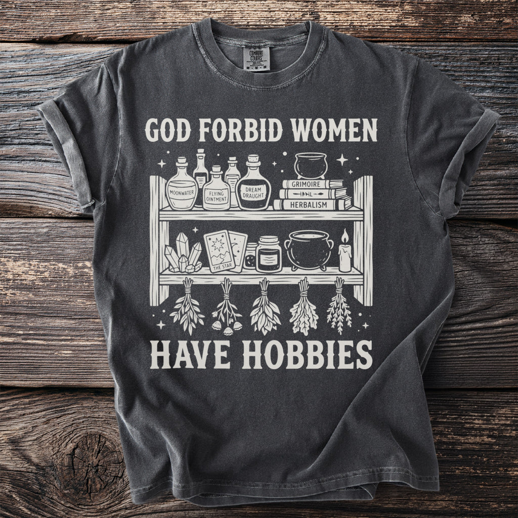 Dark grey t-shirt with "GOD FORBID WOMEN HAVE HOBBIES" and witchy graphics.