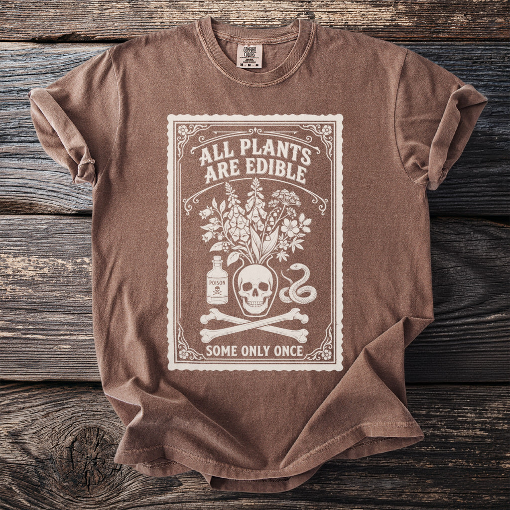 Brown t-shirt with white graphic of skull, plants, poison bottle, snake, and bones.