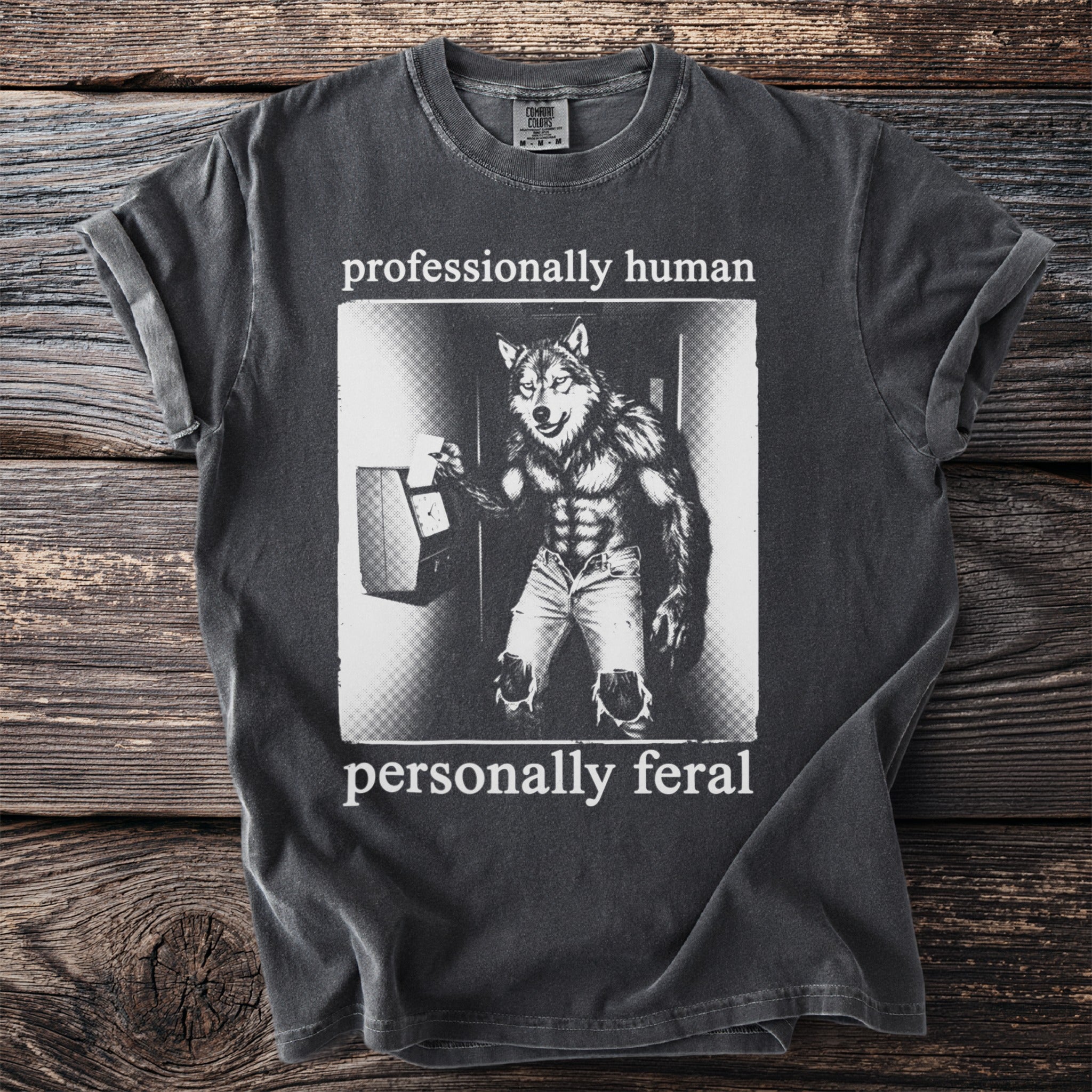 Dark grey t-shirt with a werewolf punching a time clock, text "professionally human personally feral".