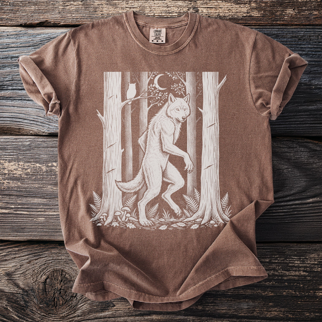 Werewolf graphic on a brown t-shirt with trees, moon, owl, and mushrooms.