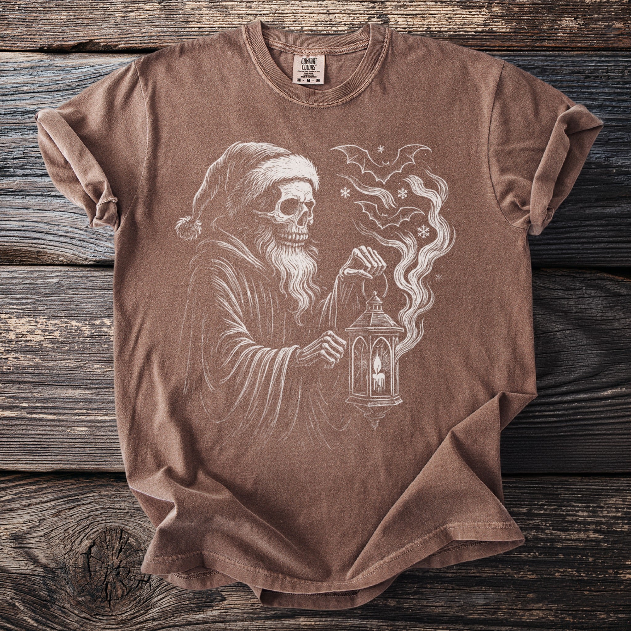 Brown t-shirt featuring a sketch of a skeletal figure in a Santa hat holding a lantern.
