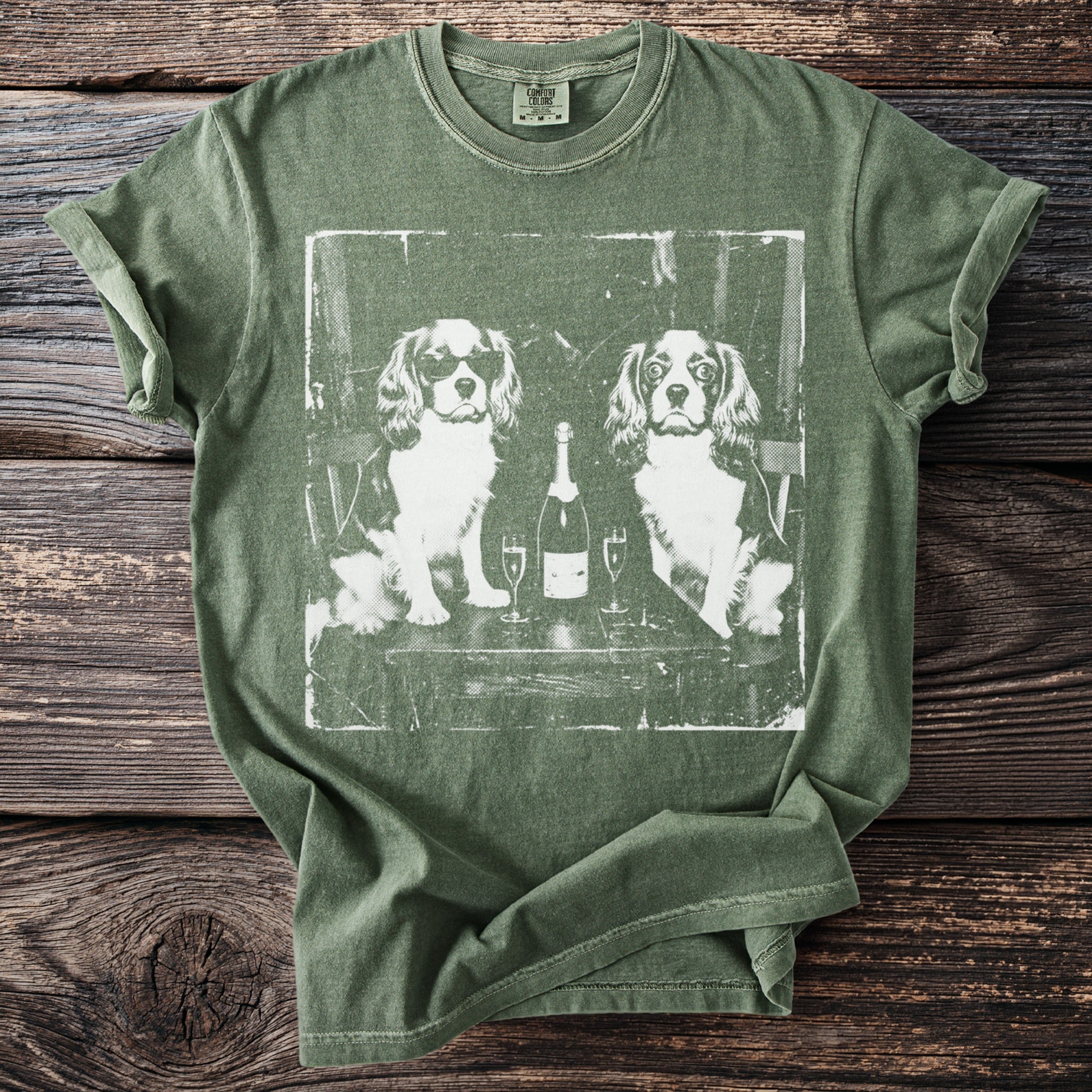 Olive green t-shirt with graphic of two dogs, champagne bottle, and glasses.