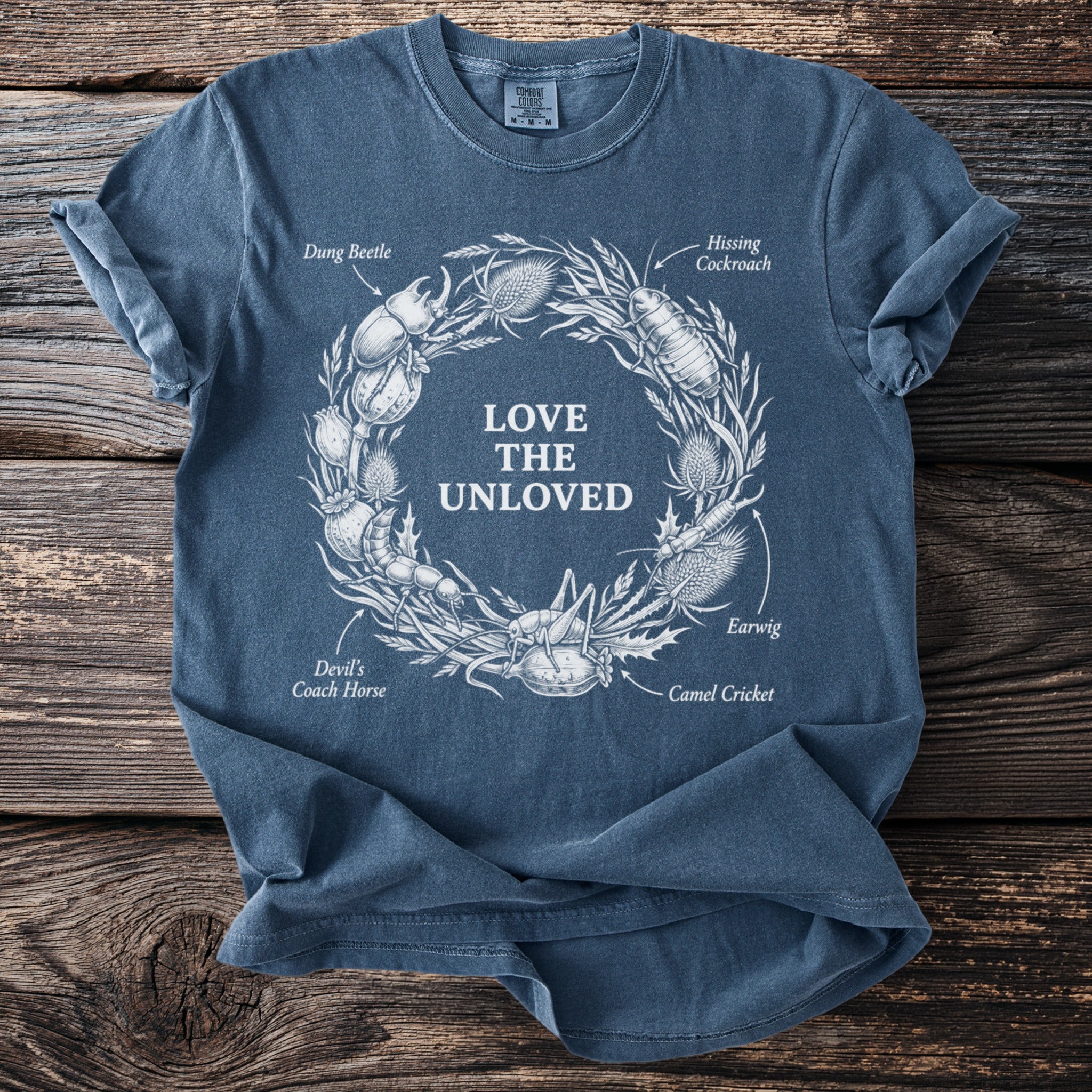 Blue t-shirt with white illustration of insects in wreath and text "LOVE THE UNLOVED".