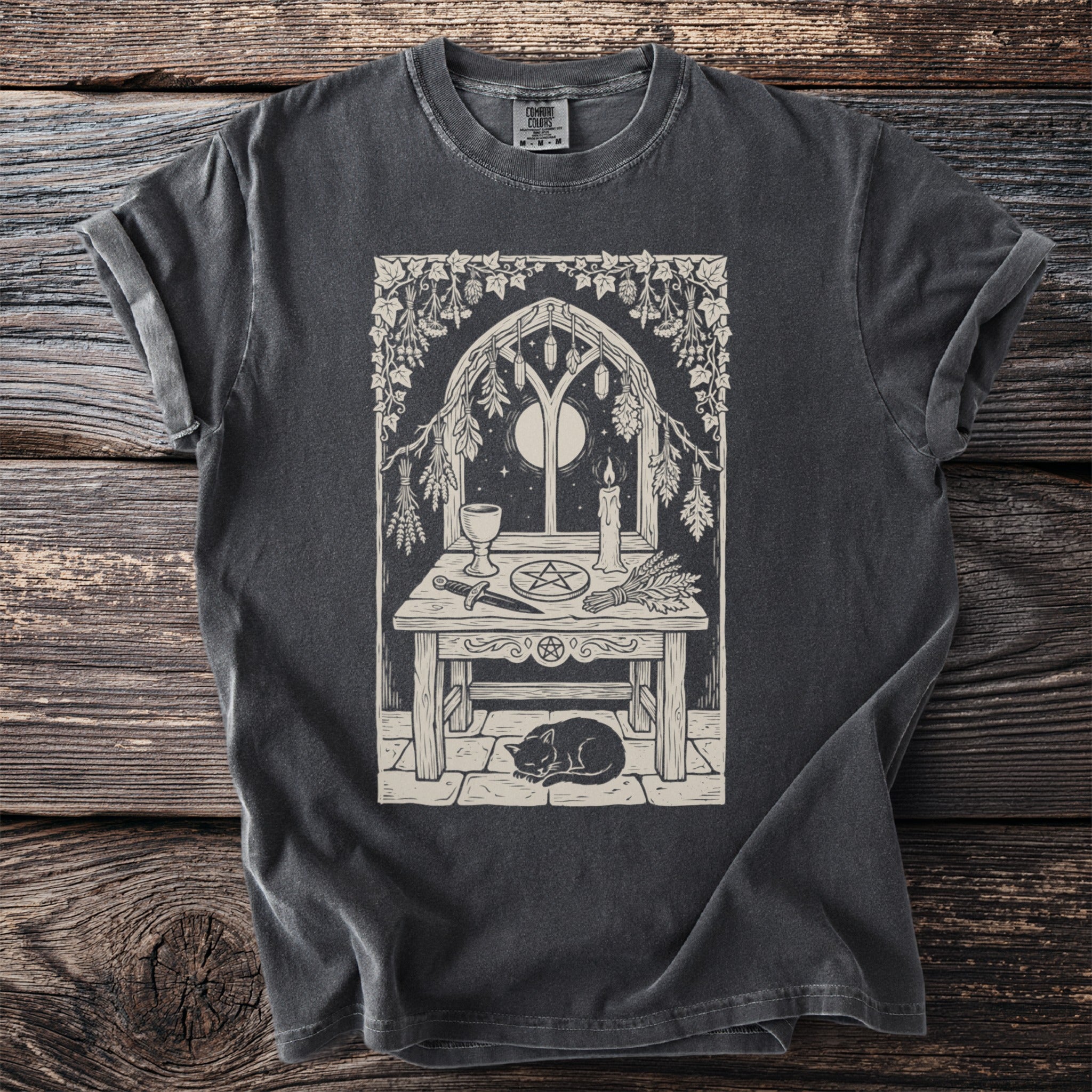 T-shirt featuring a pentagram altar scene with a cat, moon, and candle.