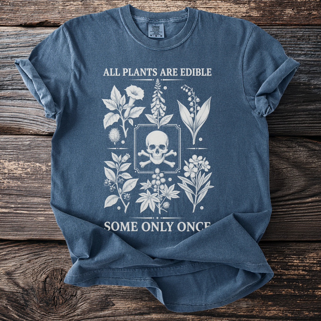 Blue t-shirt with white botanical illustrations and skull, reading "ALL PLANTS ARE EDIBLE SOME ONLY ONCE".