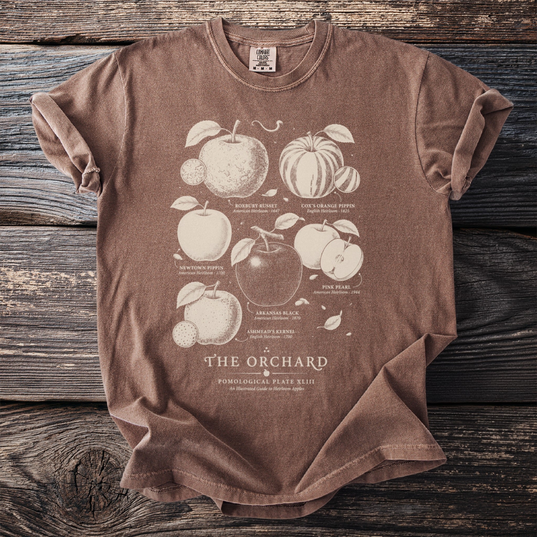 Brown t-shirt with "The Orchard" and illustrated heirloom apples.