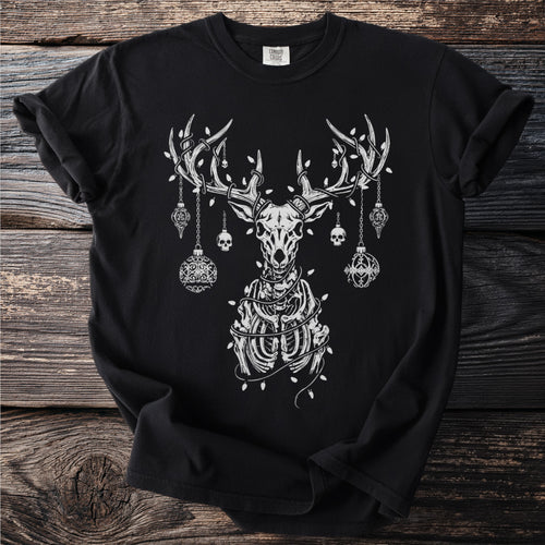 Black t-shirt with skeletal deer, skulls, and ornaments on wooden background.