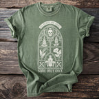Green t-shirt with Gothic window design, skull, plants, poison bottle, and text.