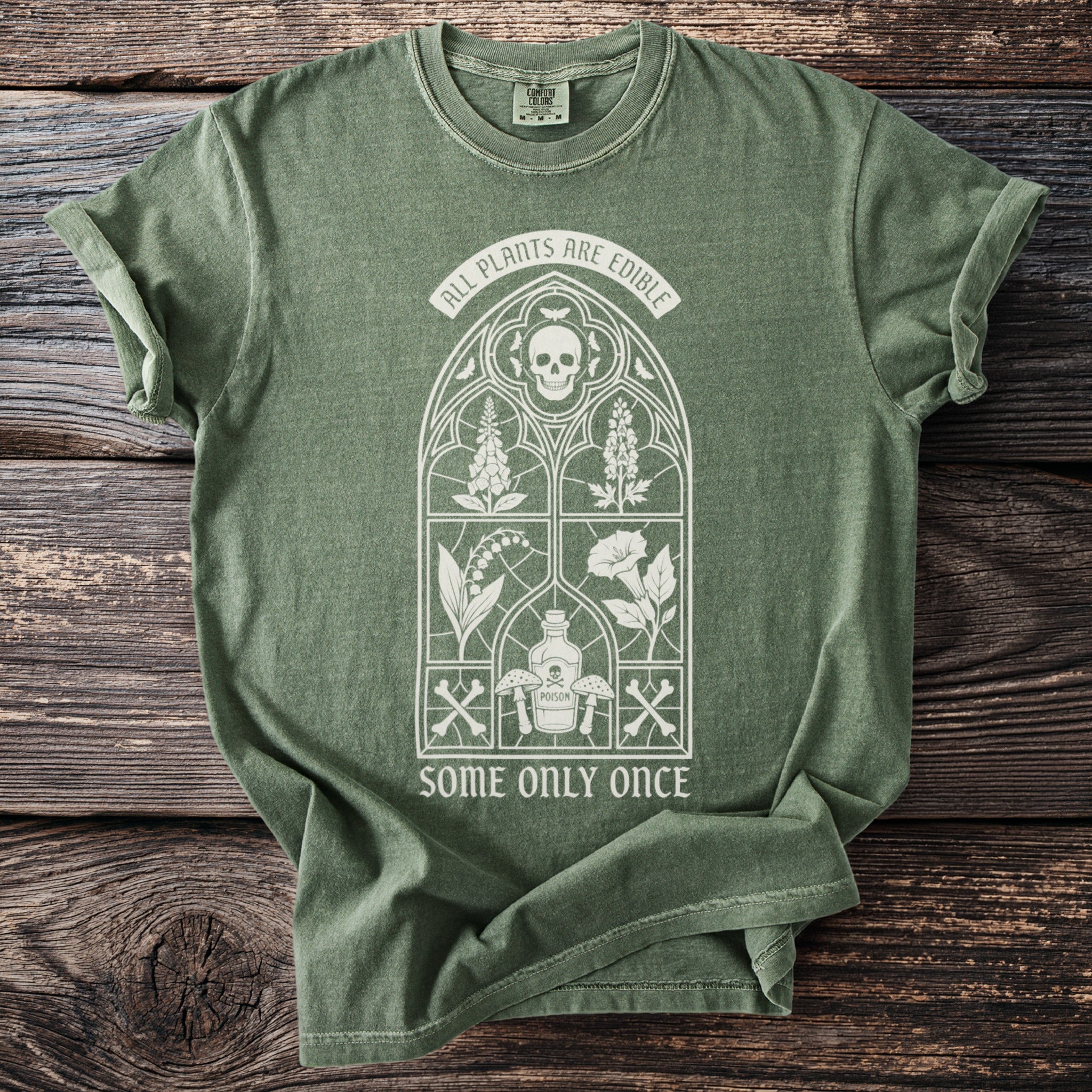 Green t-shirt with Gothic window design, skull, plants, poison bottle, and text.