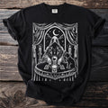 Black t-shirt with white occult image of hooded figure, crystal ball, and cat.