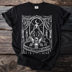 Black t-shirt with white occult image of hooded figure, crystal ball, and cat.