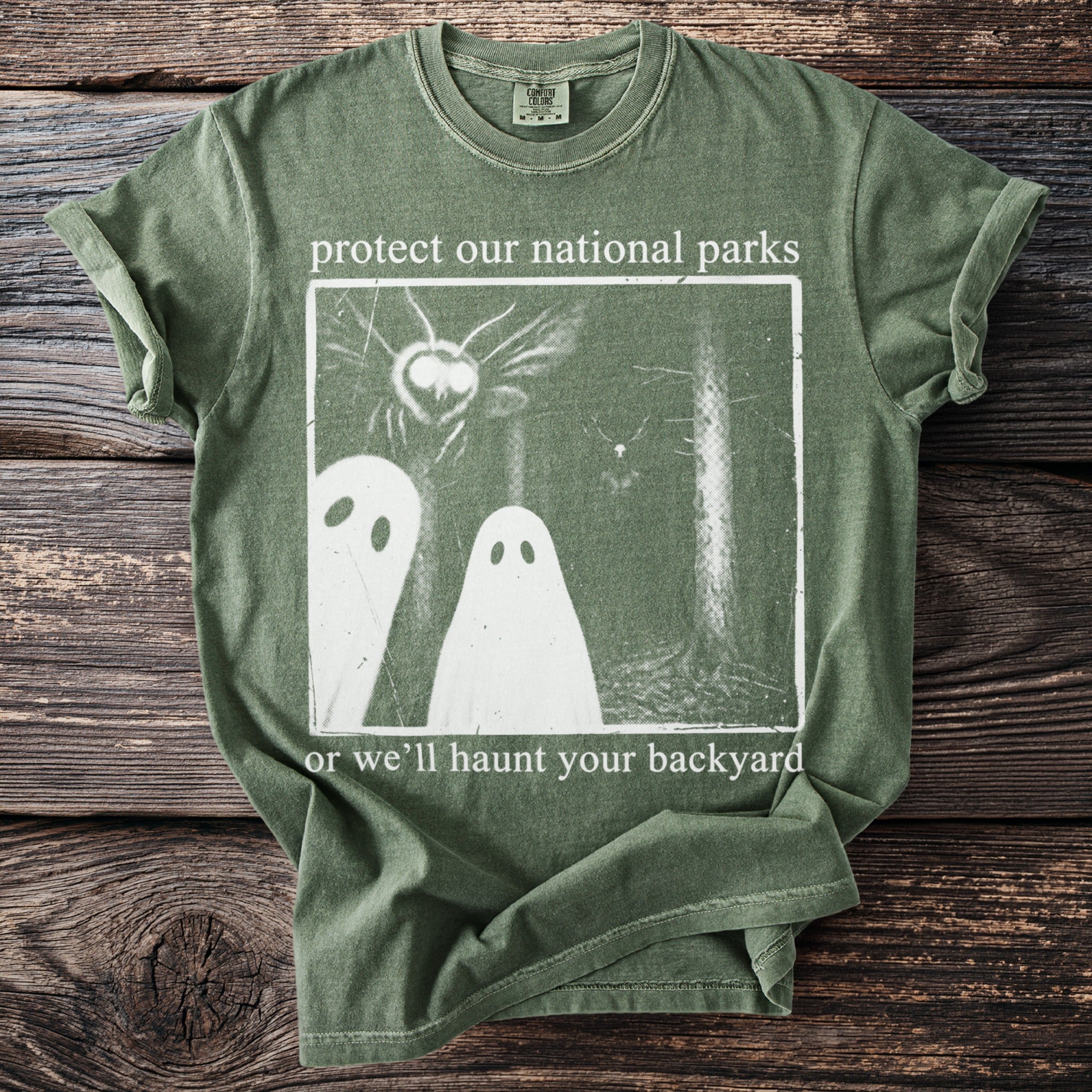Green t-shirt with "protect our national parks or we'll haunt your backyard" text and ghost graphic.