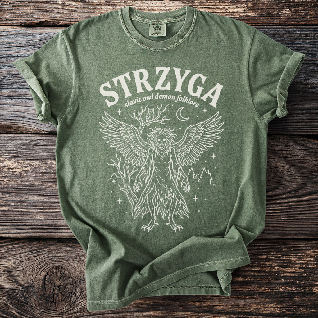 Green t-shirt with "STRZYGA slavic owl demon folklore" and winged creature illustration.