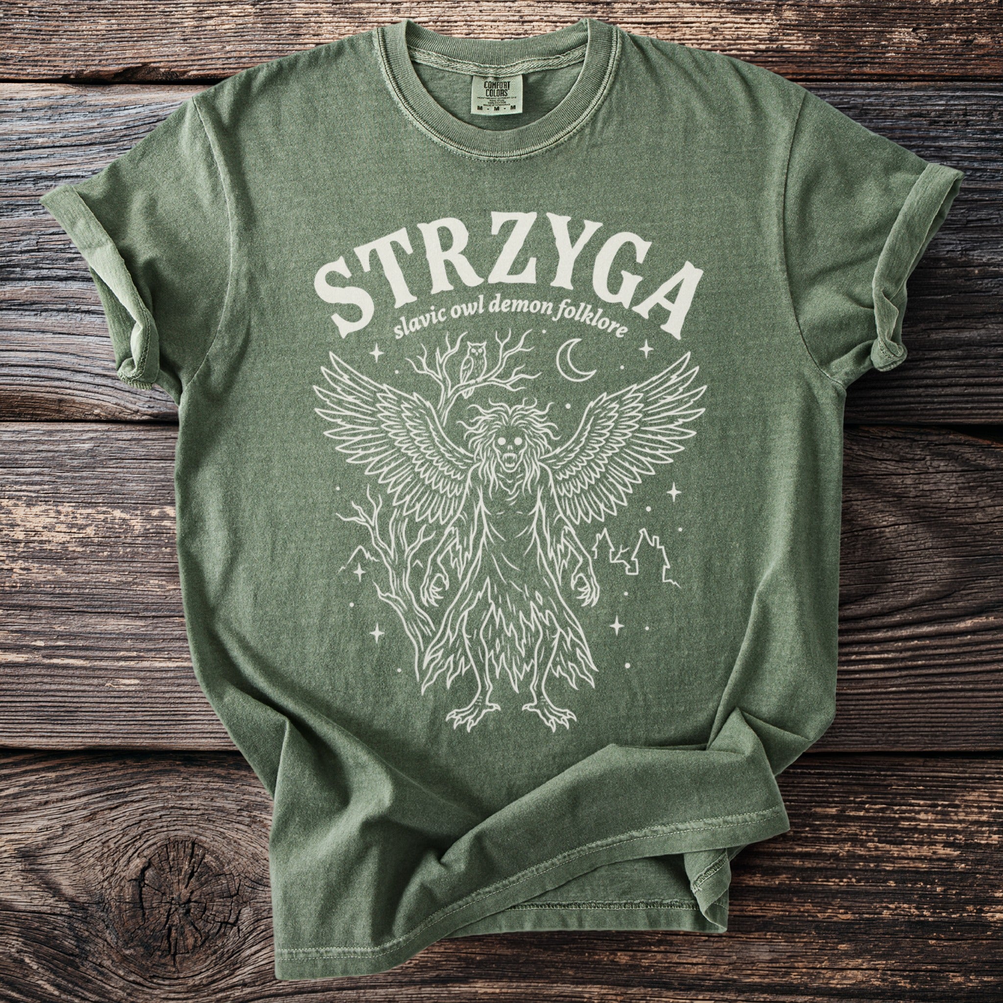 Green t-shirt with "STRZYGA slavic owl demon folklore" and winged creature illustration.