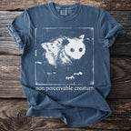 Blue t-shirt with a graphic of an opossum with butterfly wings and the text "non perceivable creature".
