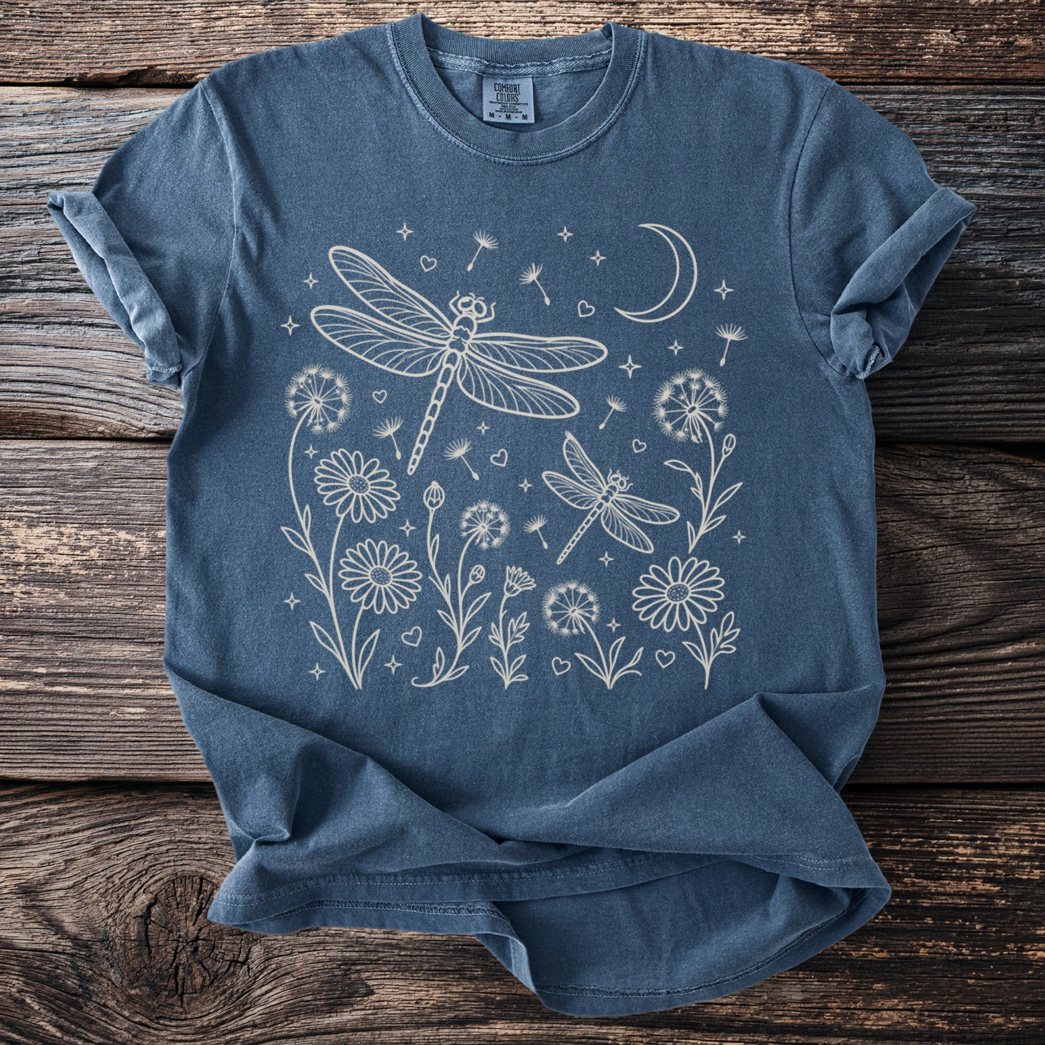 Dark blue t-shirt with line art of dragonflies, flowers, dandelions, and moon.