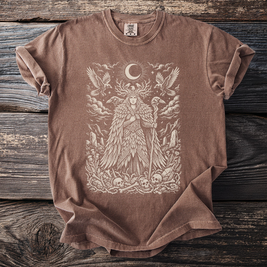 Brown t-shirt with a graphic of a woman with antlers, moon, birds, and skulls.