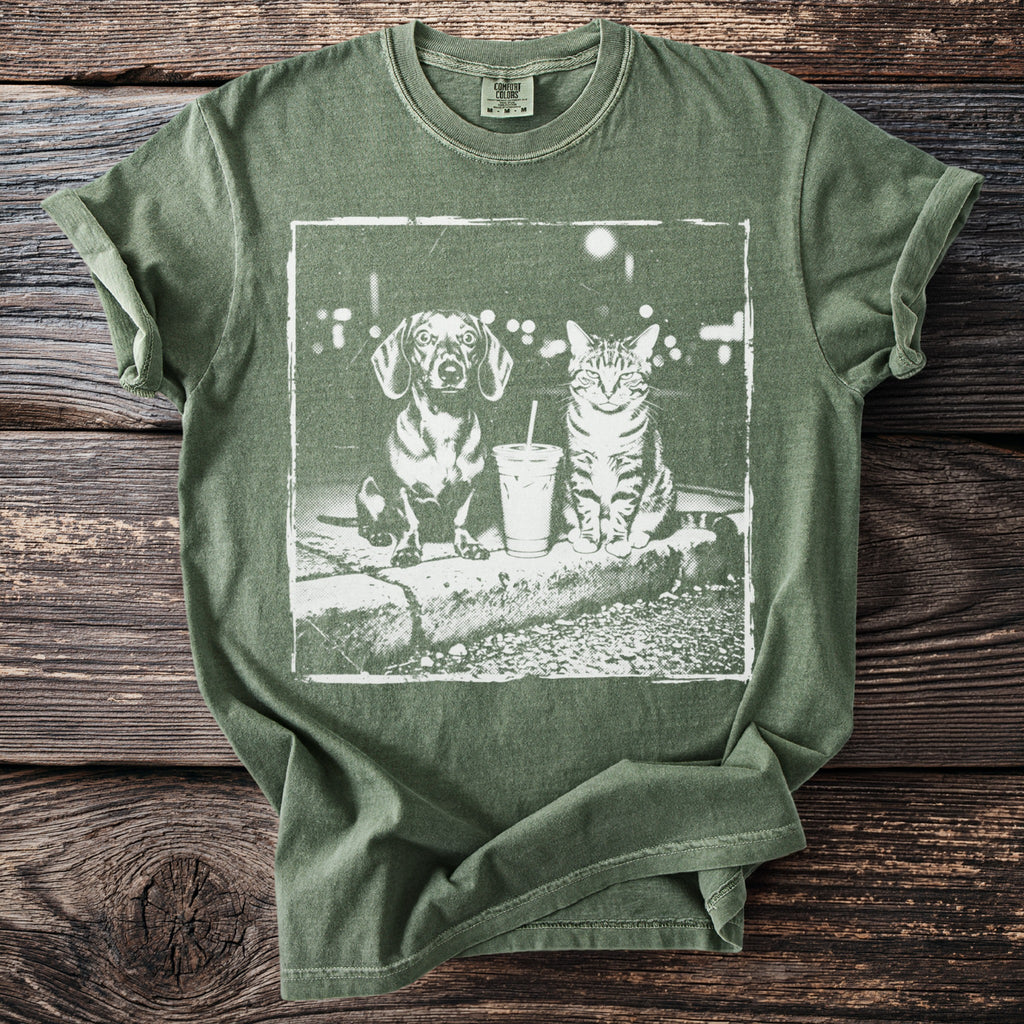 Green t-shirt with a white, distressed graphic of a dachshund and a tabby cat sitting by a drink.