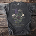 Dark t-shirt with a botanical illustration of poisonous plants and their names, titled "The Poison Garden".