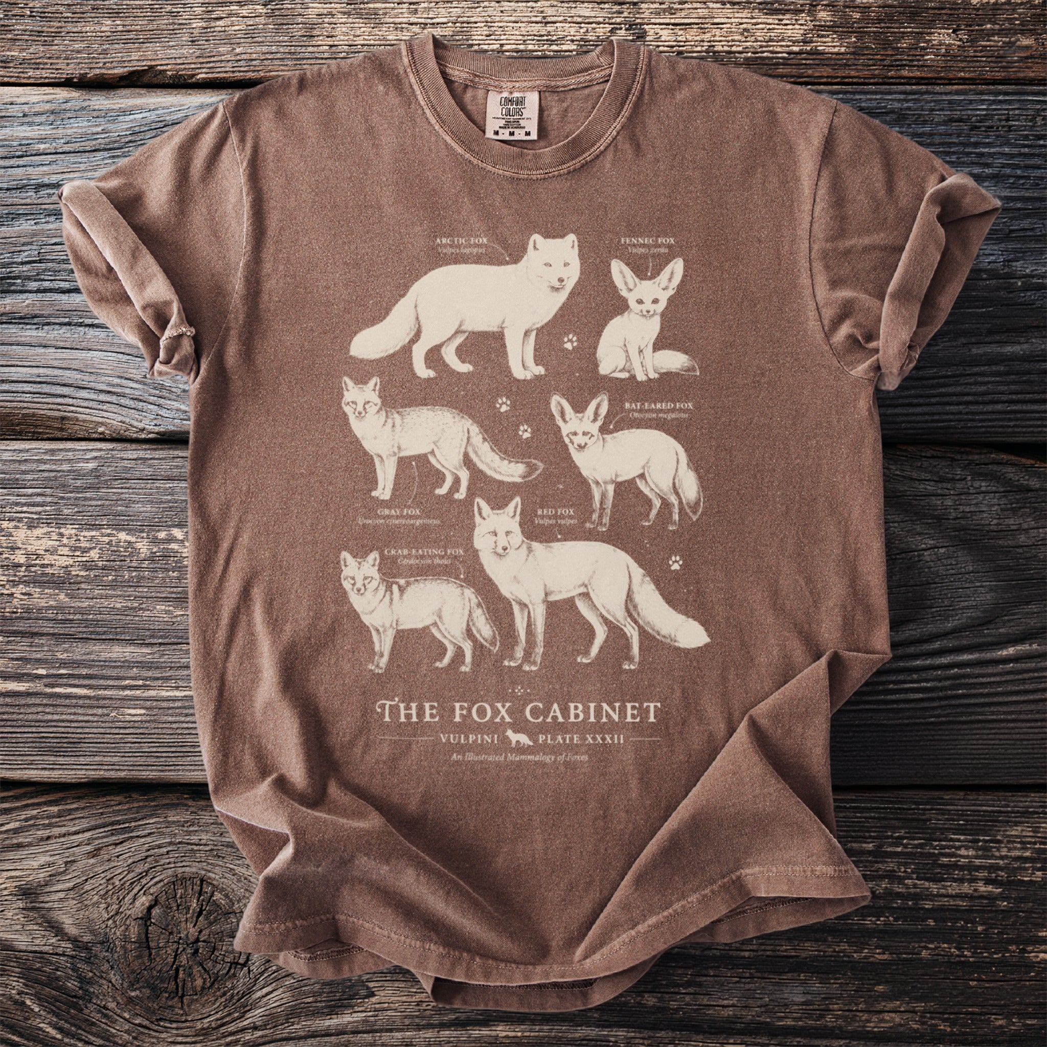 Brown t-shirt with illustrations of six different fox species and text "The Fox Cabinet".