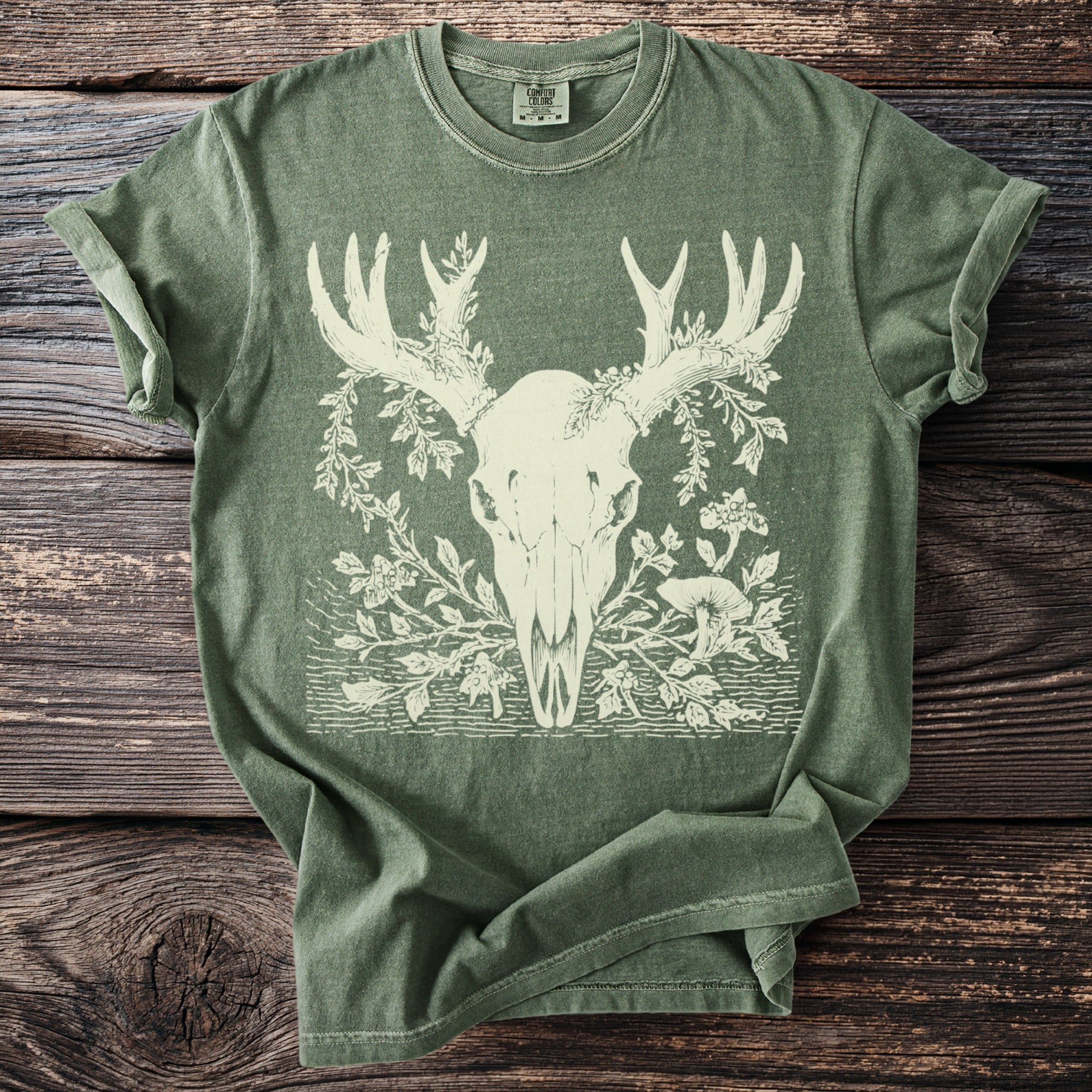 Green t-shirt with cream deer skull, antlers, and floral design.