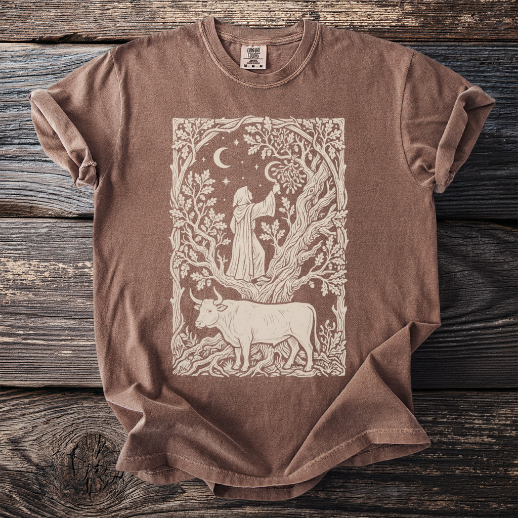 Brown t-shirt with illustration of a robed figure reaching for fruit under a crescent moon above a bull.