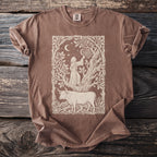 Brown t-shirt with illustration of a robed figure reaching for fruit under a crescent moon above a bull.