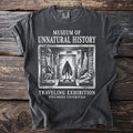 Dark t-shirt with "Museum of Unnatural History" and exhibition graphics.