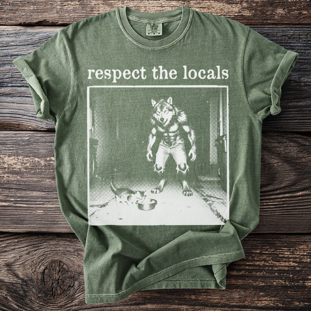 Green t-shirt with "respect the locals" text and wolf-man offering food to a cat.