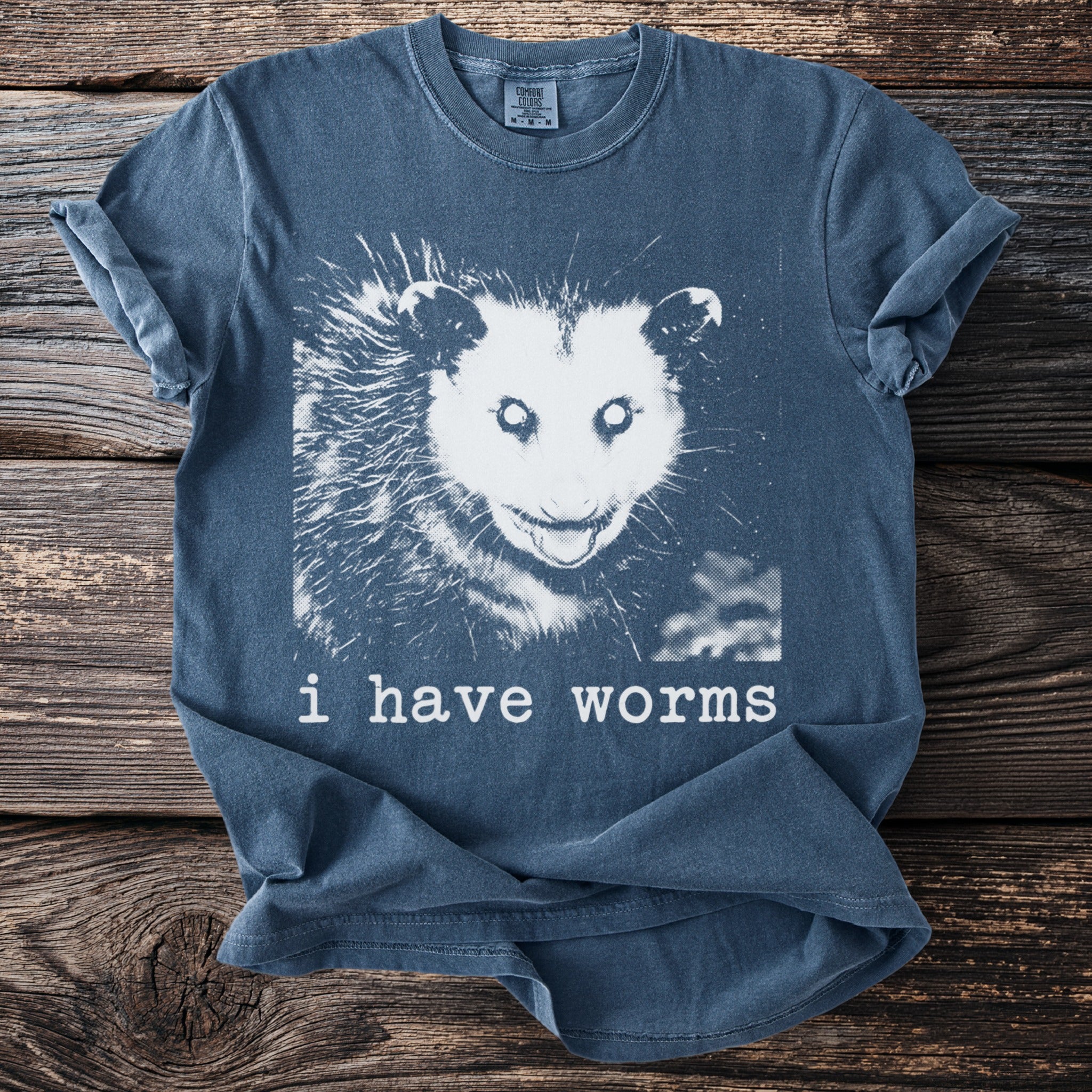 Blue t-shirt with black and white opossum graphic and text "i have worms"