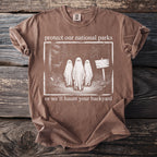 Brown t-shirt with "protect our national parks or we'll haunt your backyard" text and ghost graphic.
