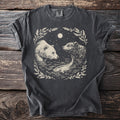 T-shirt with cream graphic of two bears and a fish in water under moon.