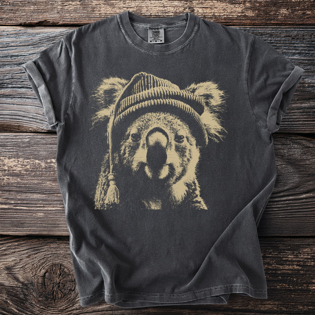 Dark t-shirt featuring a screen print of a koala wearing a beanie with a tassel.